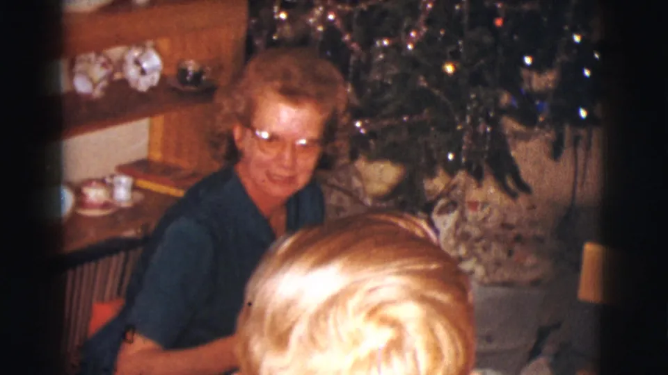 In the final frame, the woman smiles near the Christmas tree as a blond child is partly seen from behind in the foreground.