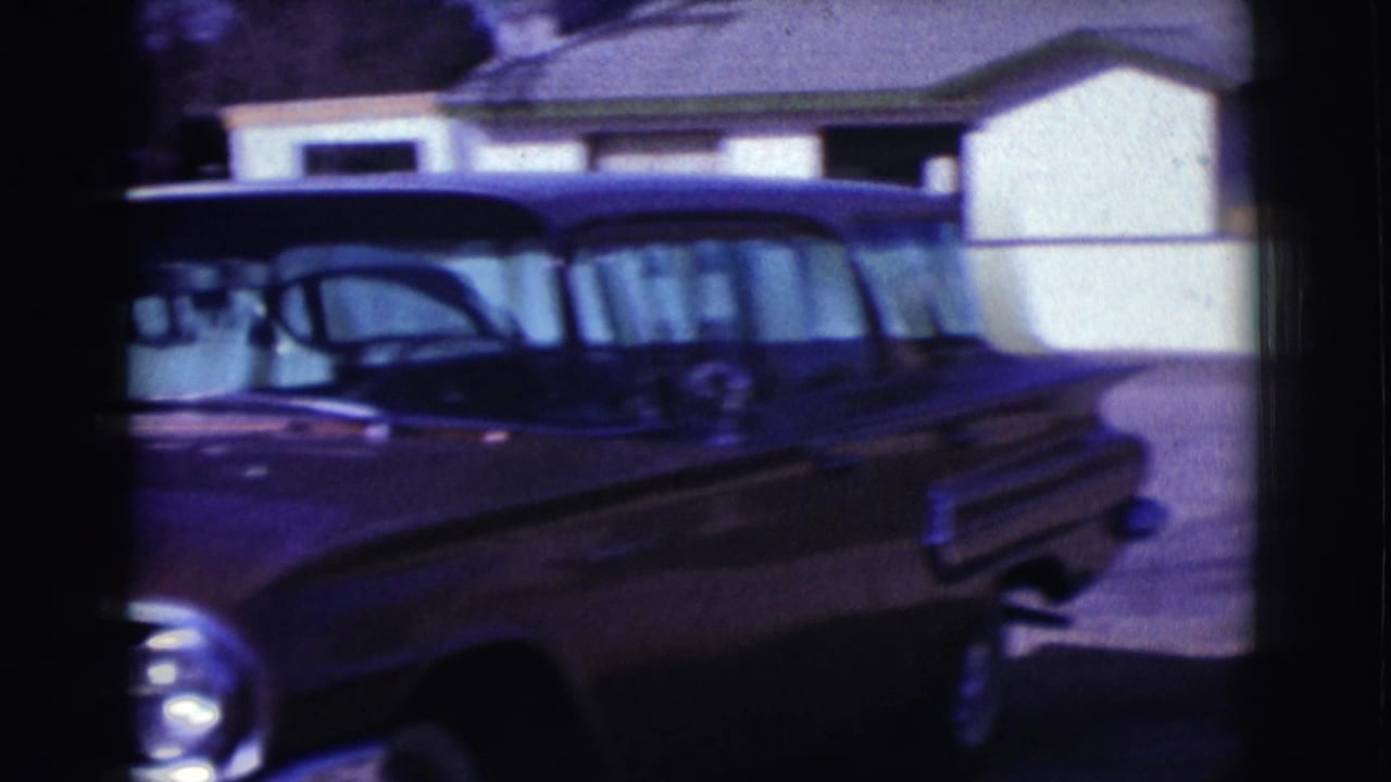 Dark mid-century station wagon seen from the side in the 1961 Clarkdale residential street footage.