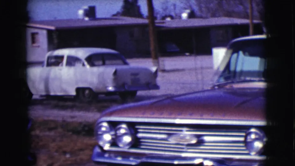 Rear of the white sedan in a Clarkdale neighborhood, with another car in the foreground and a low house behind it.