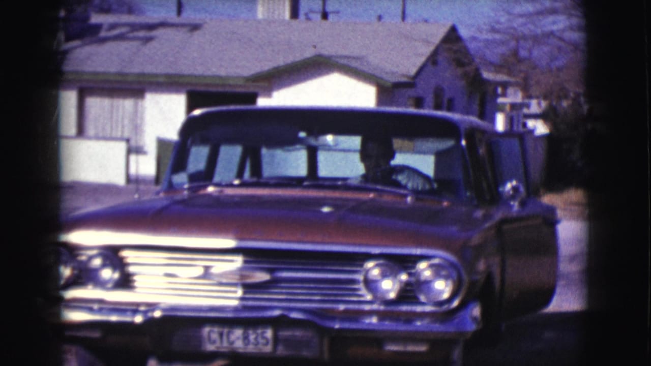 Red classic sedan facing camera in a driveway with a house behind it.