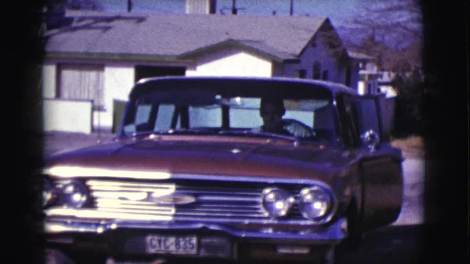 1961 Clarkdale, Arizona home-movie frame showing a red classic sedan facing the camera in a residential driveway.