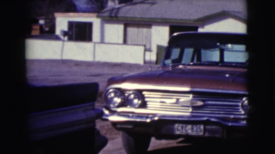 1961 Clarkdale, Arizona home-movie frame showing the sedan partly framed by another dark car body in the foreground.