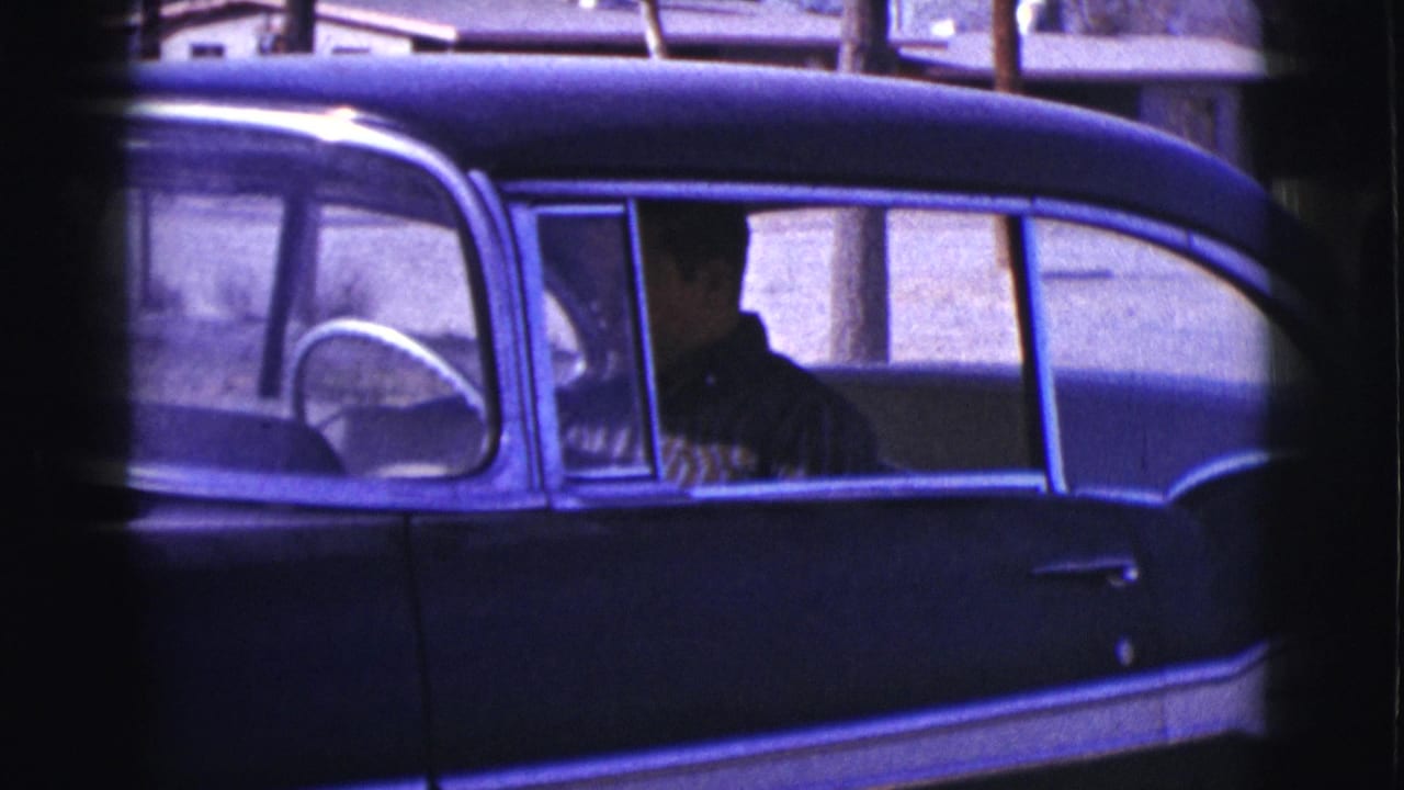 Closer side view of the dark sedan with the seated driver area visible.