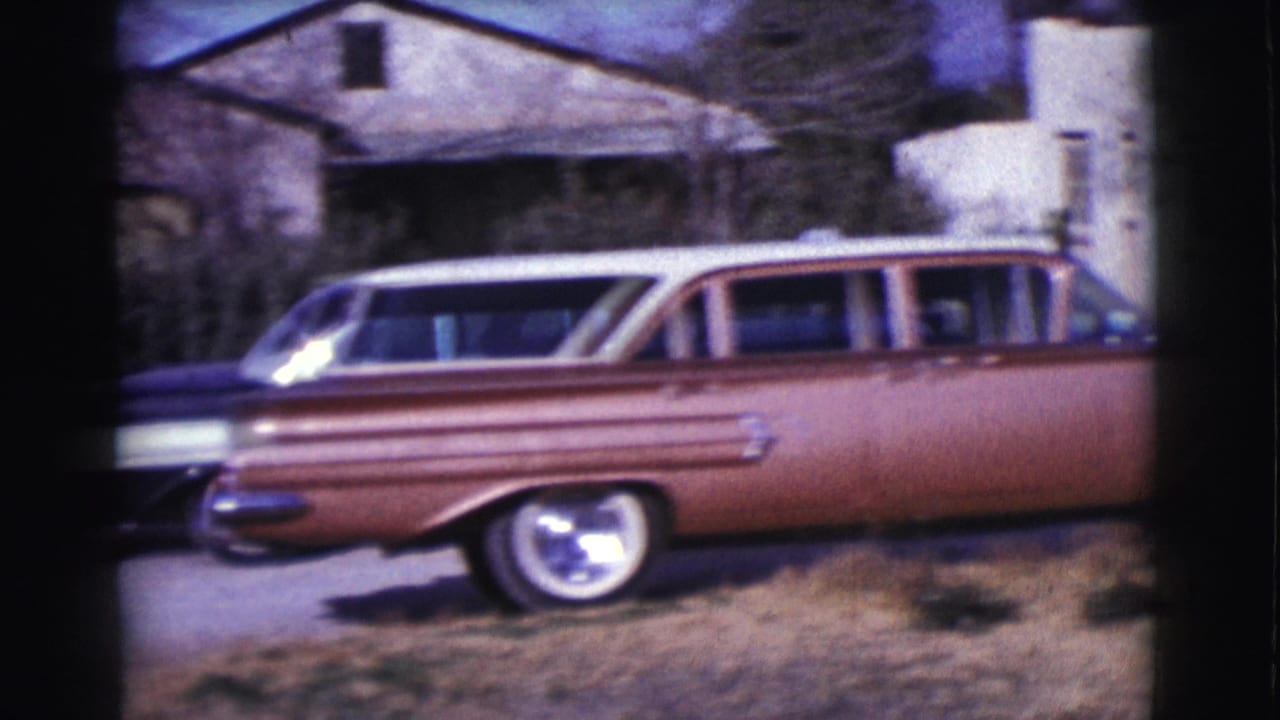 Brown station wagon parked beside a low residential building.