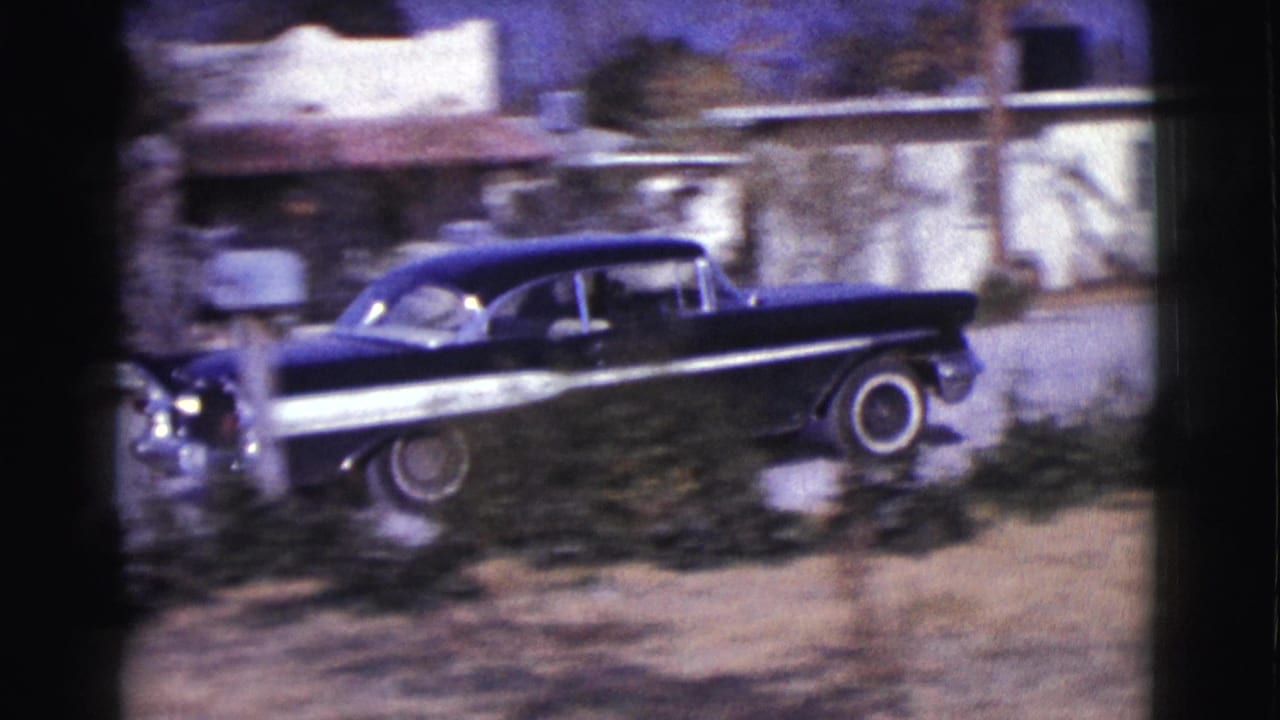 Black mid-century sedan appears near low houses in Clarkdale, Arizona, with chrome detailing and whitewall tire visible.