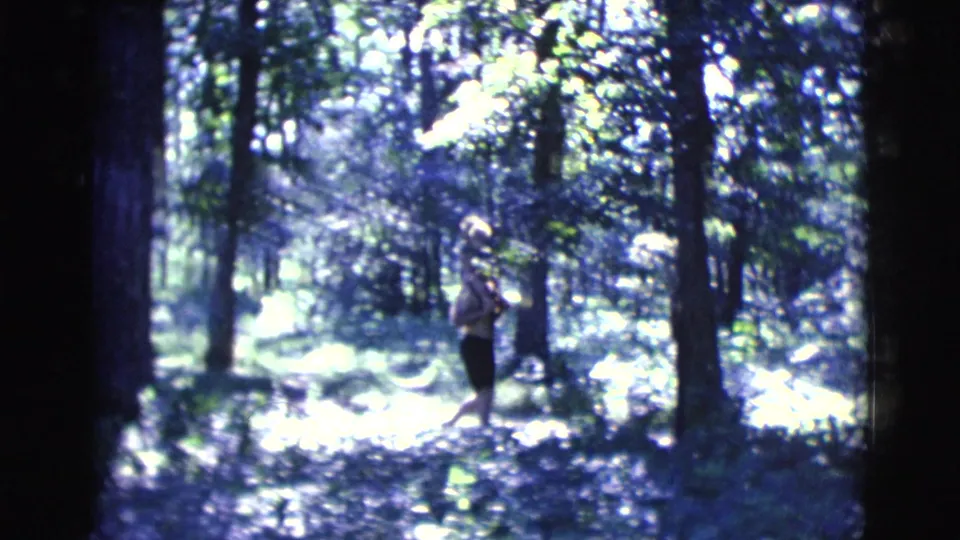 A distant woman walks through a bright, overexposed woodland path in the Clarkdale, Arizona home-movie scene.