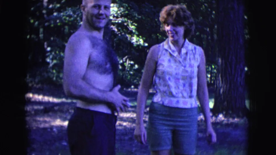 In Clarkdale, Arizona 1961 home-movie footage, a shirtless man holding a cigarette stands with a smiling woman in a sleeveless patterned top.