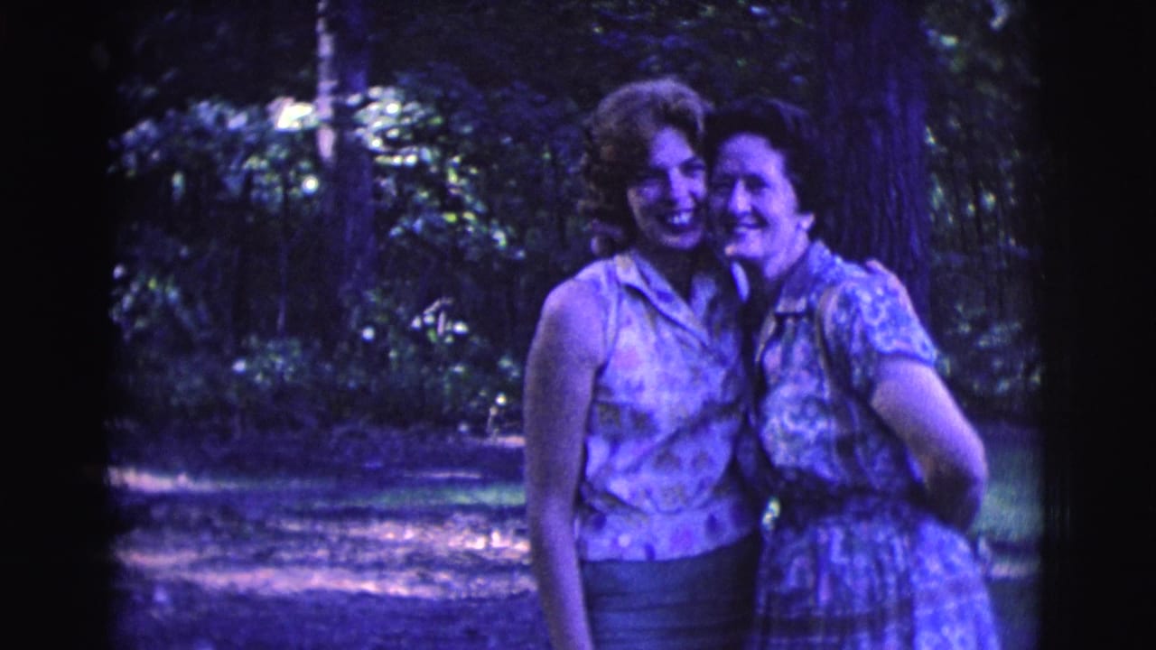 Two adult women stand arm in arm and smile in a wooded garden setting in Clarkdale, Arizona, 1961.