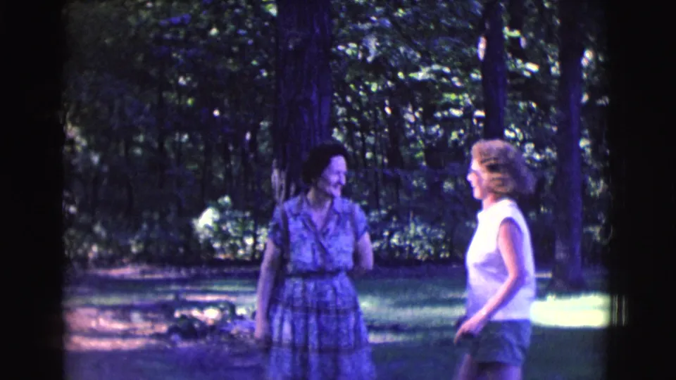 The women turn toward one another in the Clarkdale park setting, with trees and filtered sunlight behind them.