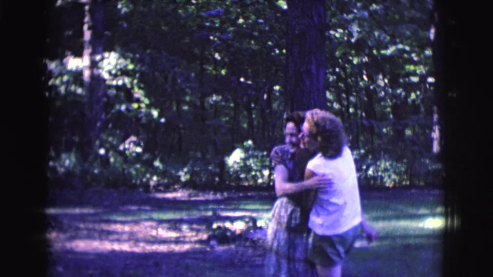 The women share a close embrace in the metadata-supported Clarkdale, Arizona park scene, surrounded by shaded grass and tall trees.