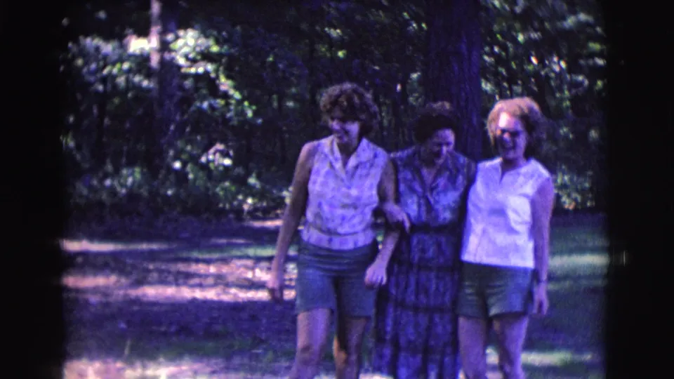 Three adult women walk together arm in arm in 1961 Clarkdale, Arizona 8mm home-movie footage.