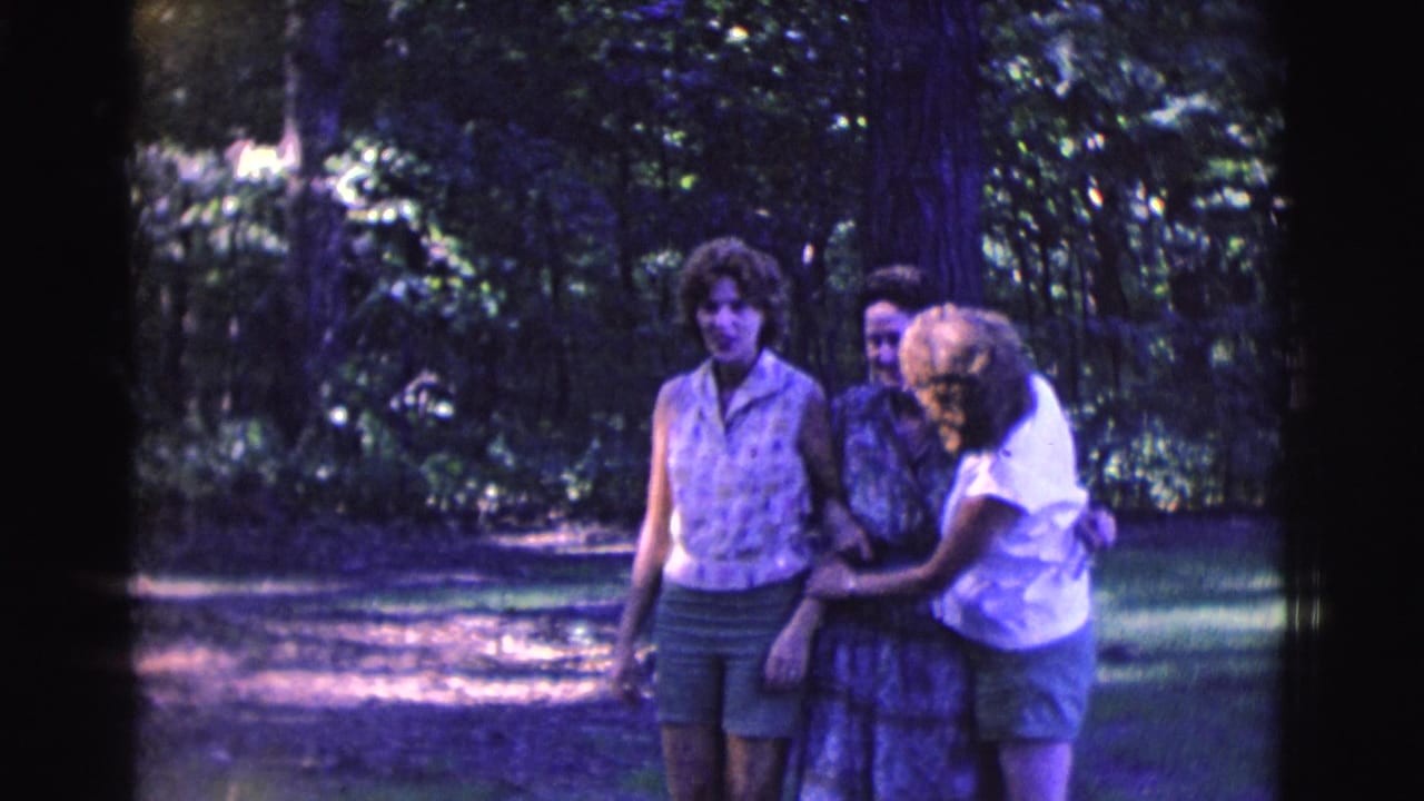 Three women stand close together outdoors, smiling as they hold arms.