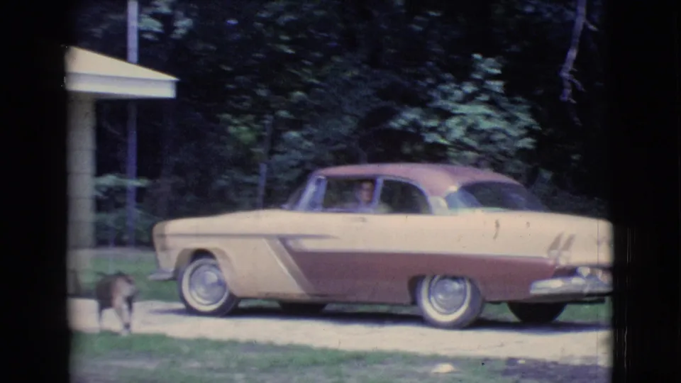 1961 Clarkdale, Arizona frame showing the car near a porch edge, with a small dog visible by the driveway.