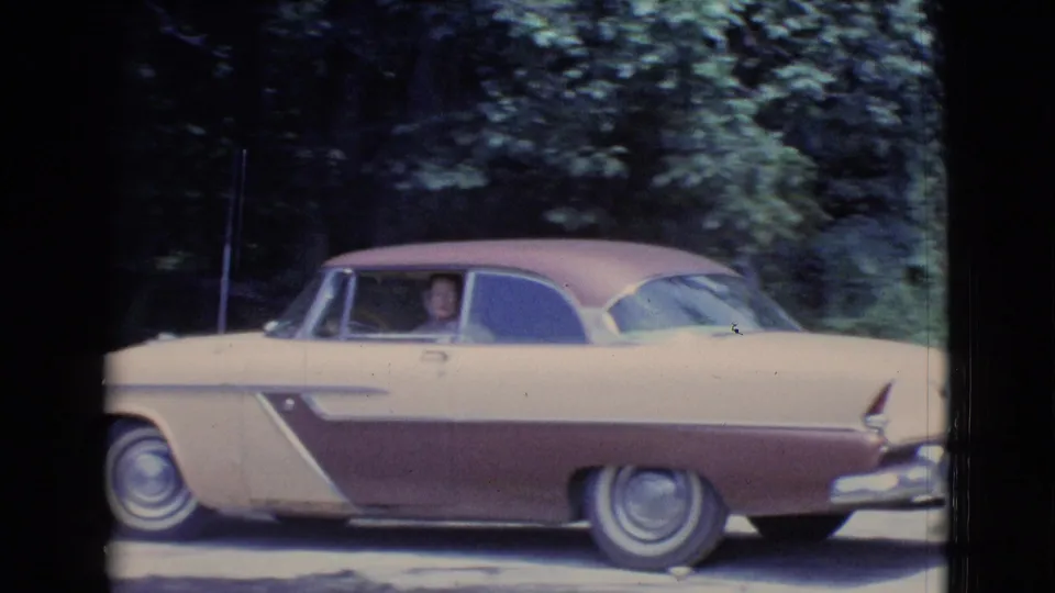 1961 Clarkdale, Arizona home-movie frame showing the driver in the two-tone car against a leafy background.