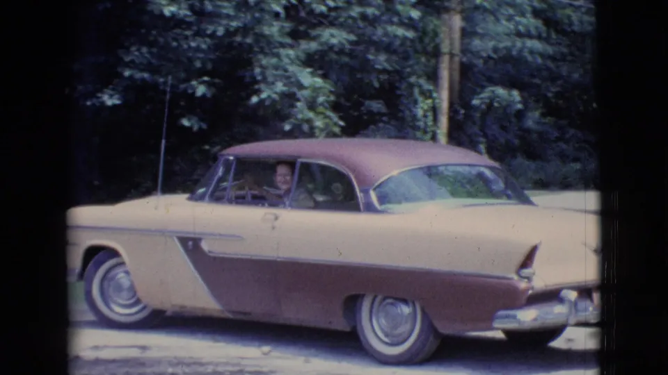 1961 Clarkdale, Arizona home-movie frame showing a two-tone sedan backing out with a woman visible through the driver window.