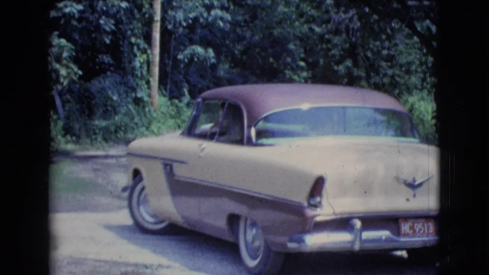 Rear view of the 1961 Clarkdale home-movie sedan as it moves along a tree-lined driveway or road.