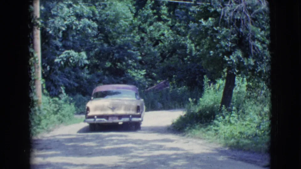 A rear view shows the mid-century sedan moving away through leafy roadside shade in the supplied Clarkdale, Arizona footage.