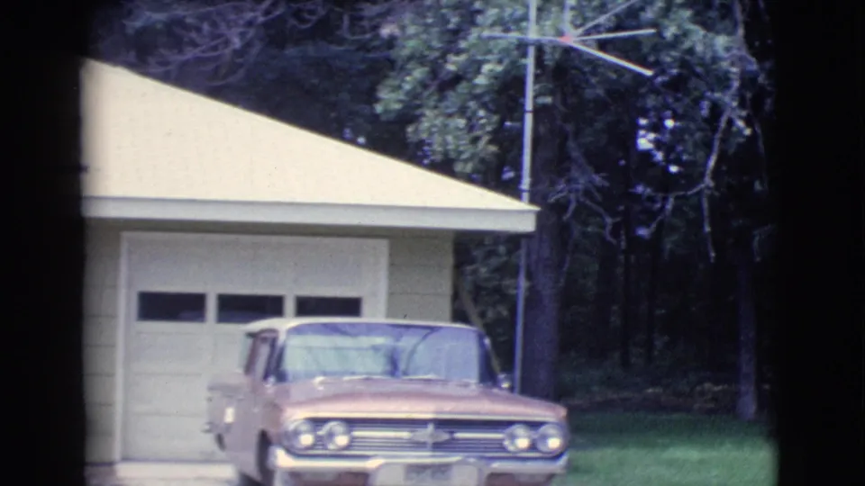 1961 Clarkdale frame centered on a yellow ranch house garage with a classic sedan parked in front and trees behind.