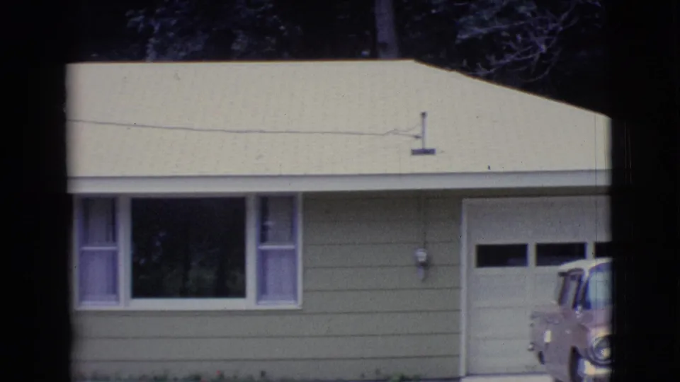 1961 Clarkdale, Arizona home-movie frame showing a light single-story house, attached garage, front window, and partial classic car.