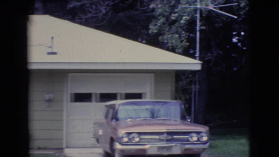 1961 Clarkdale, Arizona frame with a classic American car parked near a garage on a quiet residential property.