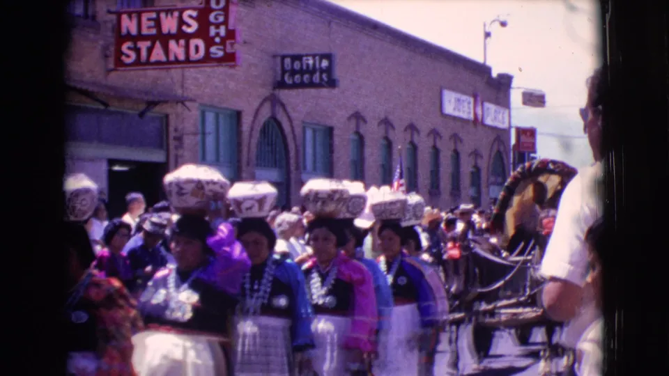 The later frame shows the women continuing through the 1961 Clarkdale parade as a horse-drawn carriage enters near the edge of the street scene.