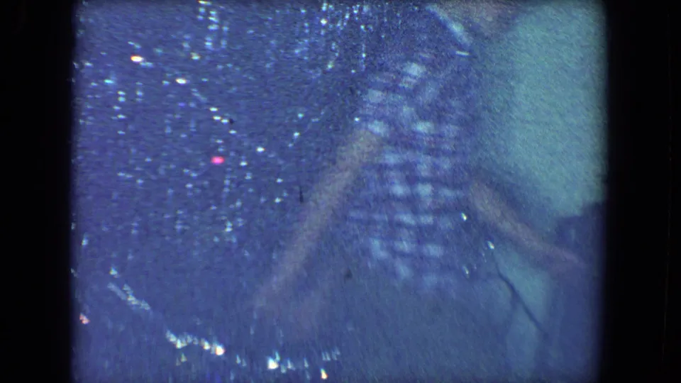 Soft 1961 home-movie frame from Salton Sea showing a person moving close to a tinsel-covered Christmas tree indoors.