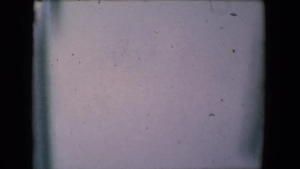 Soft 8mm frame from the 1961 Salton Sea home movie showing a pale interior surface with dust, grain, and exposure variation.