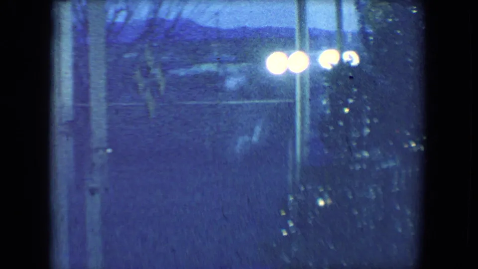 Blue-tinted 1961 Salton Sea frame with Christmas tree tinsel, glowing bulbs, and a dim window or doorway beyond.