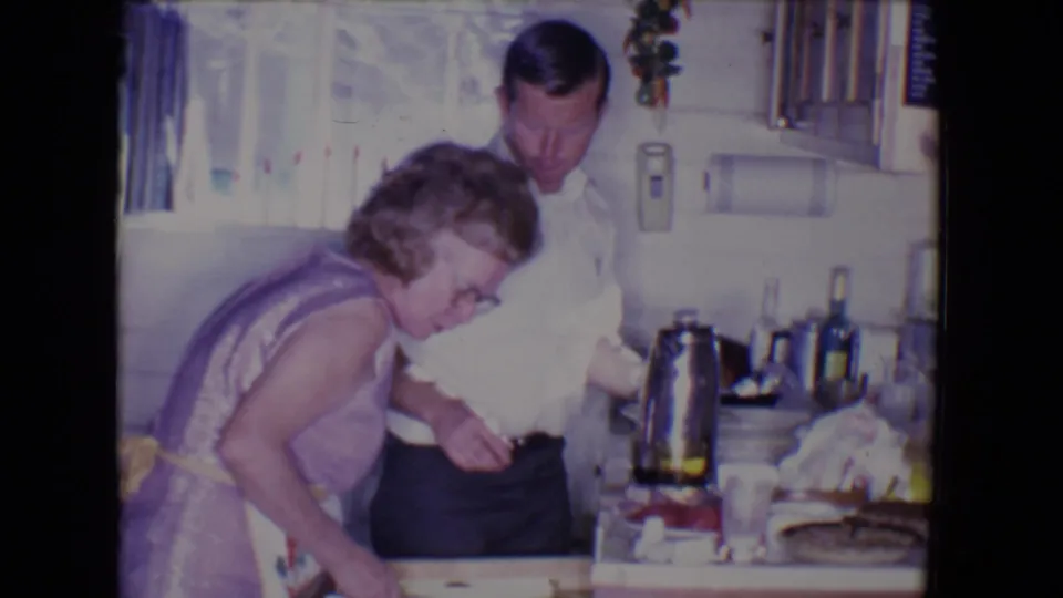 The adults stand close together in the kitchen, with the woman near the drawer and the man partly behind her by the counter.