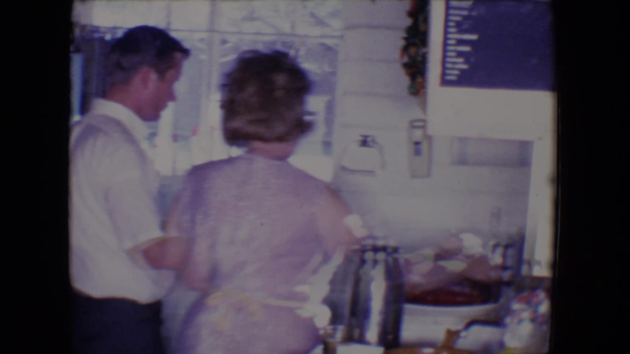 Man and woman stand at a kitchen counter with a roasted turkey nearby.