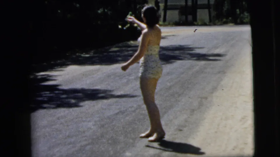 A side view shows the woman extending one arm after a throwing motion on a sunlit, tree-shadowed road in Camden metadata.