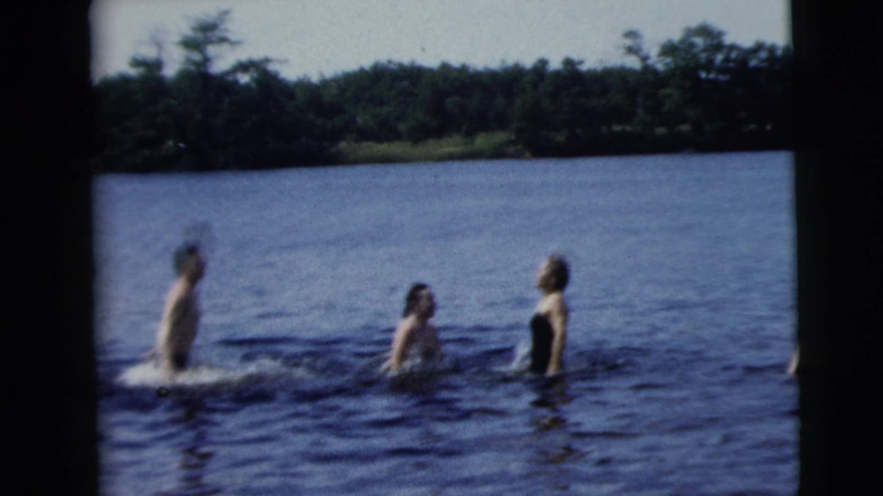 Three adults stand and splash in lake water.
