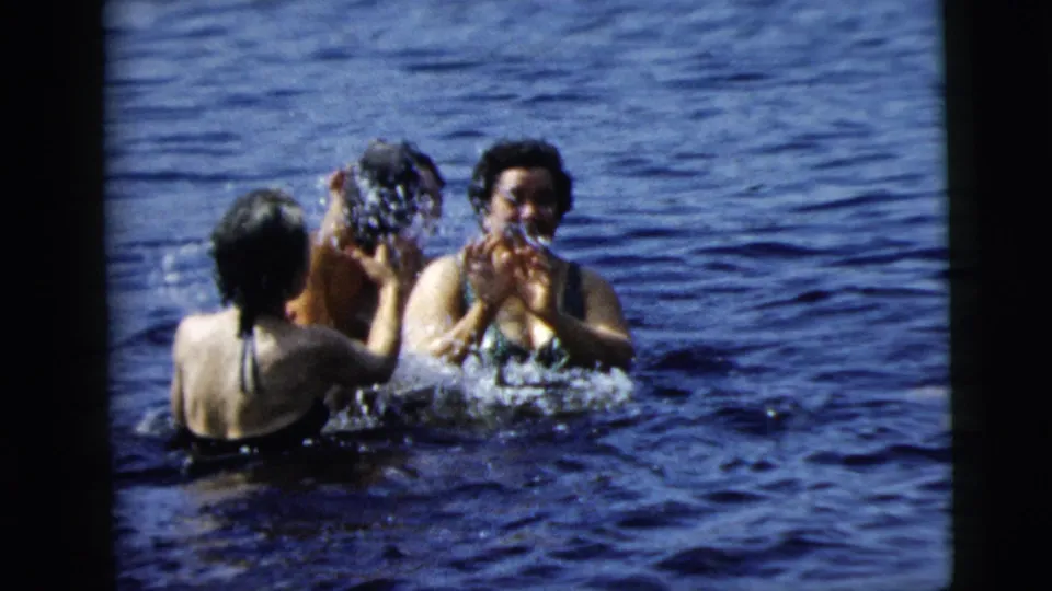 1962 Camden, New Jersey home-movie frame showing swimmers in open water, including one person throwing water toward another.