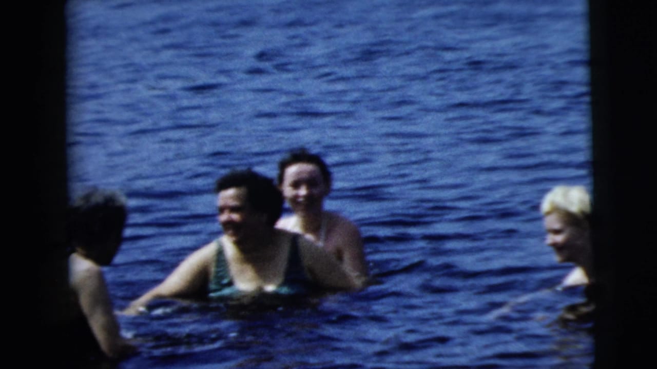 1962 8mm home-movie frame from Camden metadata showing swimmers in a lake, including women in swimsuits and a younger blond swimmer.