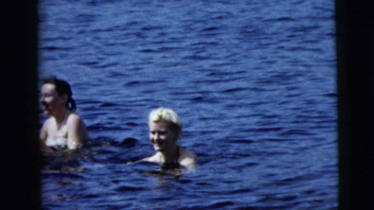 Two women, one with light hair, wade in blue water in 1962 home-movie footage associated with Camden, New Jersey.