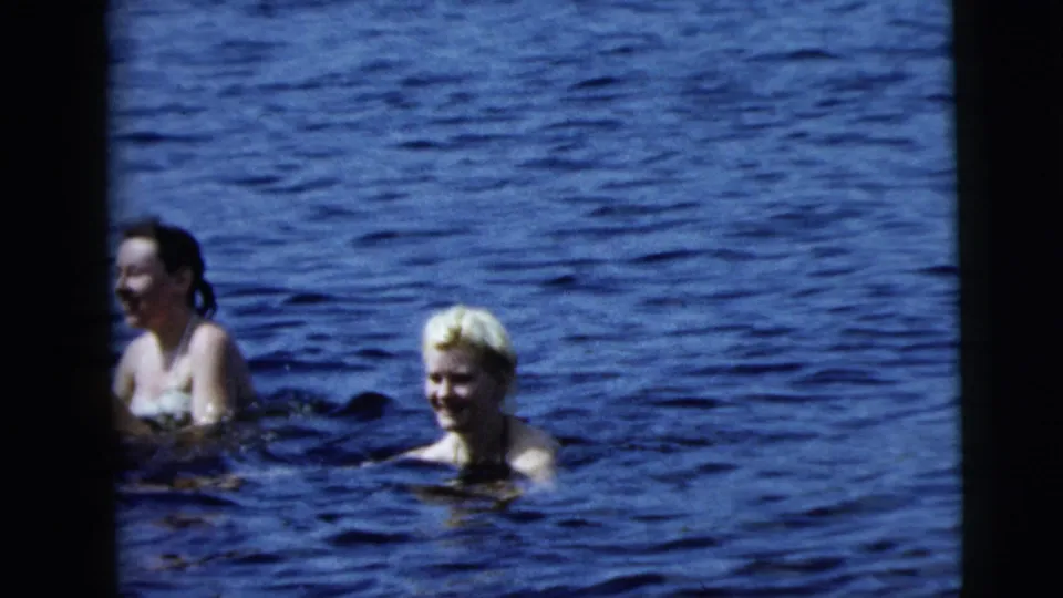 Two women, one with light hair, wade in blue water in 1962 home-movie footage associated with Camden, New Jersey.