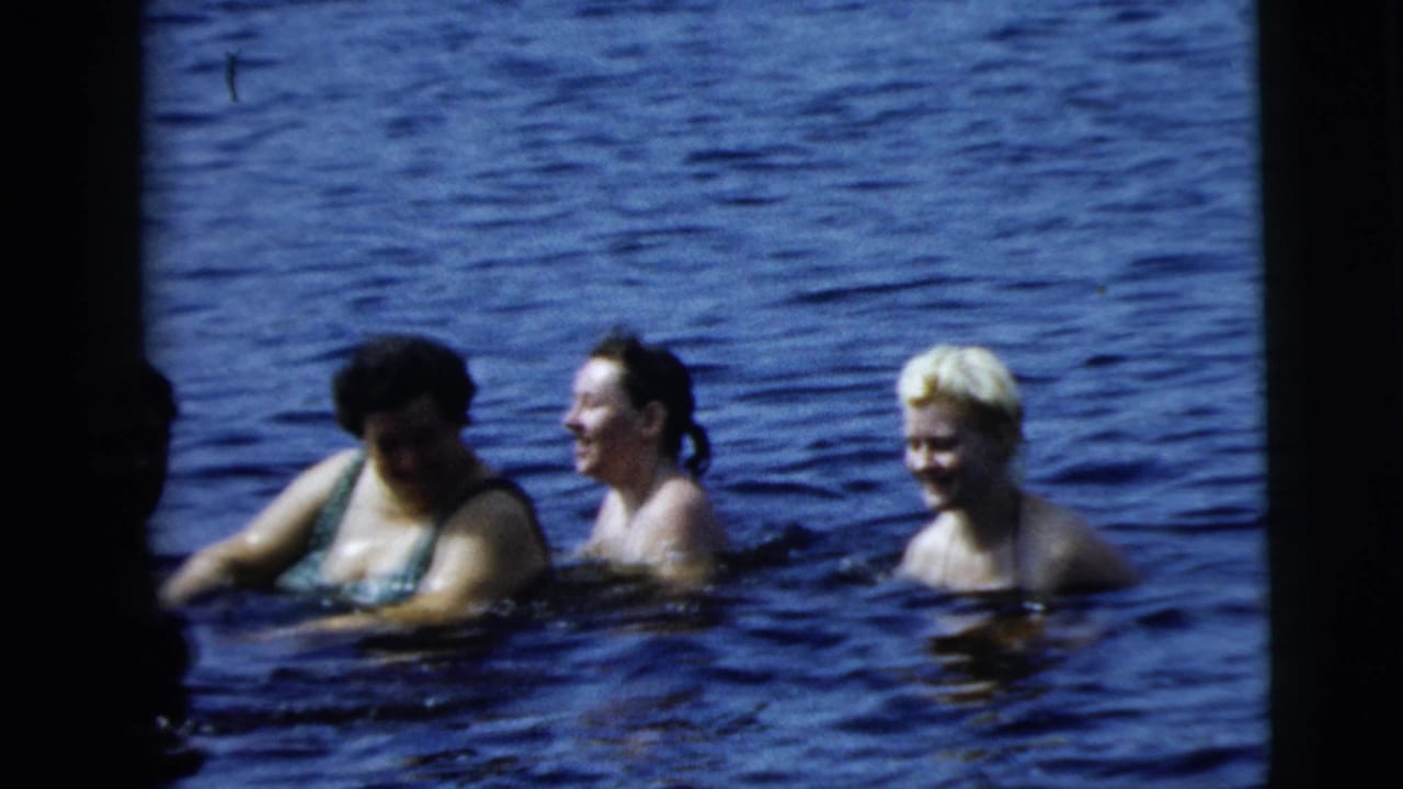 Three women wade close together in rippling blue water in 1962 8mm home-movie footage associated with Camden, New Jersey.