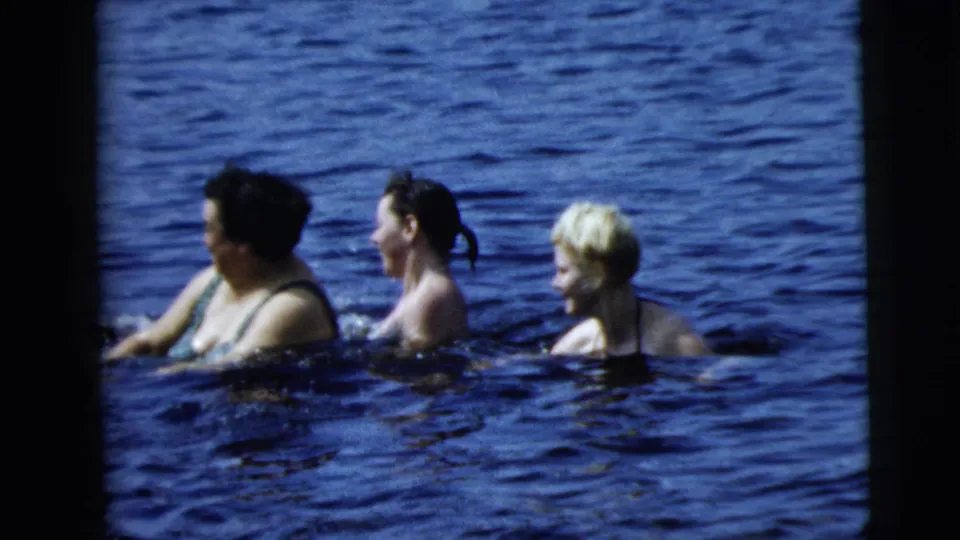 Three women move through open blue water, with one splashing, in 1962 8mm footage associated with Camden, New Jersey.