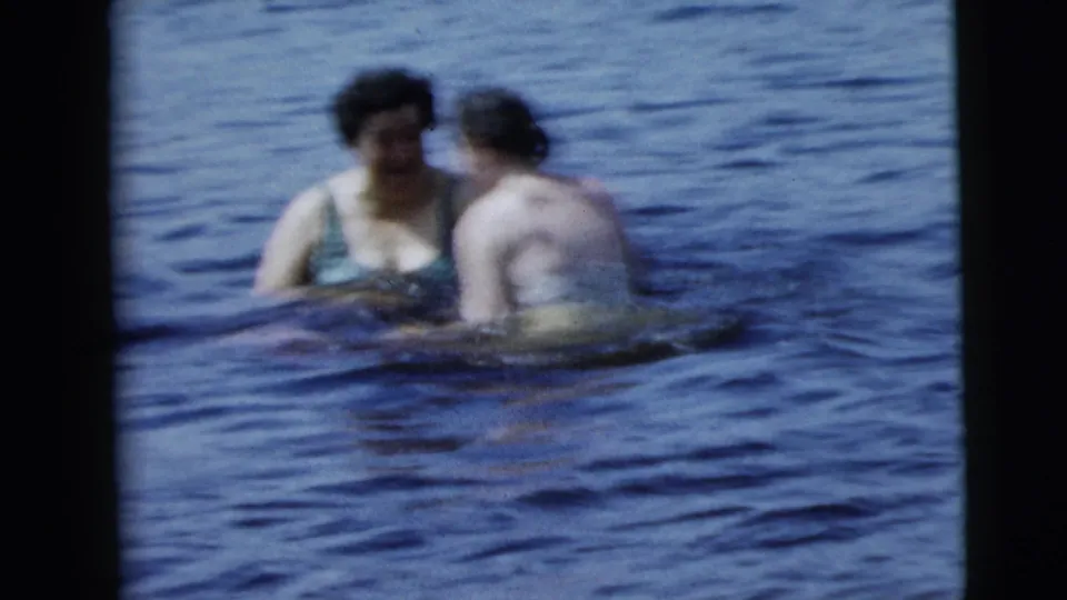 Two women face each other in rippling blue water near the end of a 1962 8mm swimming clip associated with Camden, New Jersey.