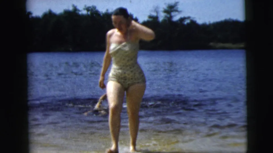 Near the end of the supported 1962 Camden lake scene, the woman exits the water while another swimmer is partly visible behind her.