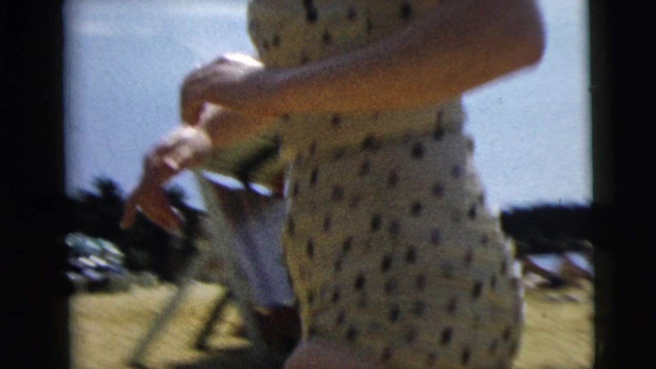 Close cropped view of a woman in a polka-dot swimsuit with another person partly visible outdoors.