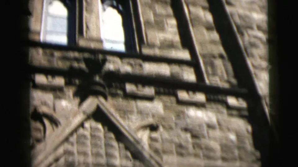 1962 Camden, New Jersey 8mm frame showing rough stone architecture, arched trim, and upper windows beside a dark foreground frame.