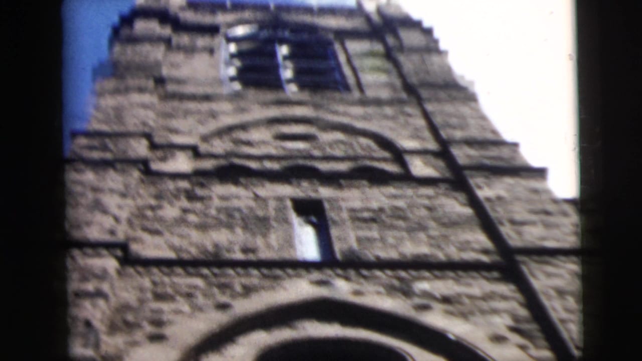 Tall stone tower photographed from below against blue sky.