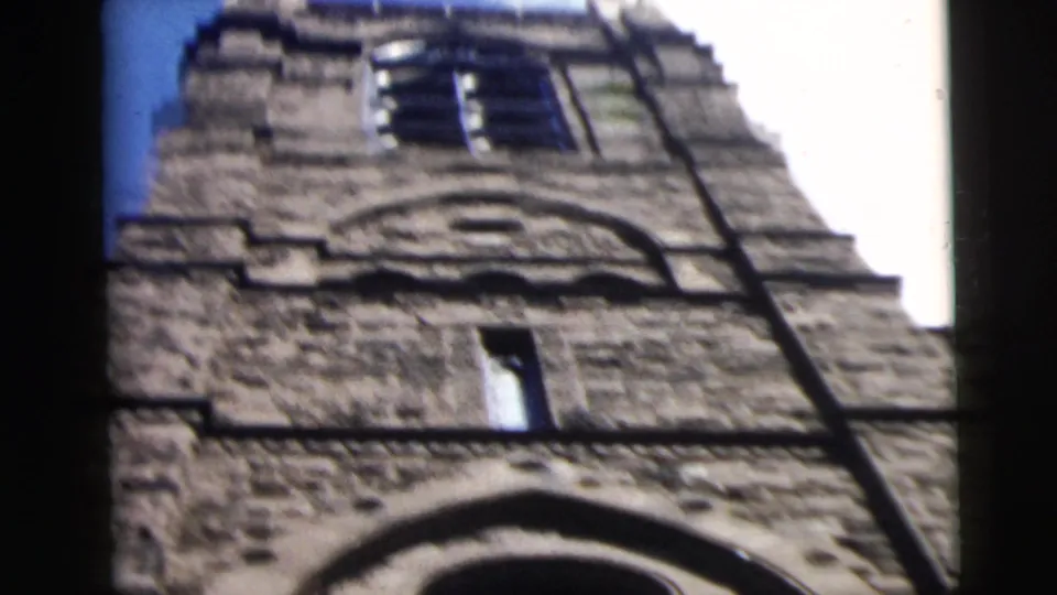 1962 Camden, New Jersey 8mm frame looking upward at a rough stone tower with dark upper windows and arched masonry.
