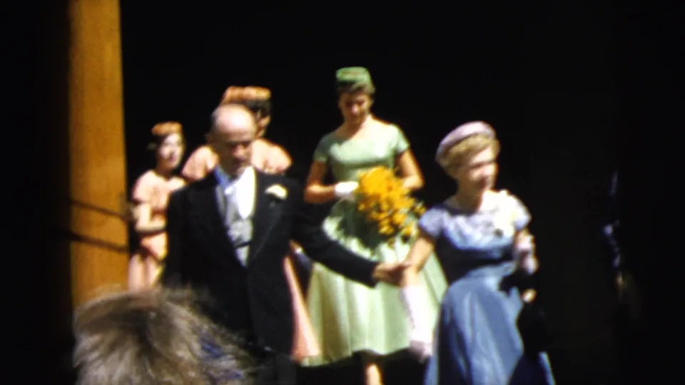 1962 Camden wedding party outside a church doorway, showing suited men, women in pastel dresses, hats, gloves, and a bouquet.