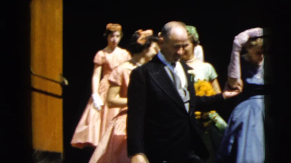 Camden 1962 wedding procession frame showing the father in front, the bride at right, and bridesmaids in pastel dresses behind.