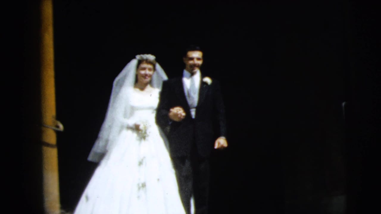 Bride and groom walk arm-in-arm down steps beside a wooden column.