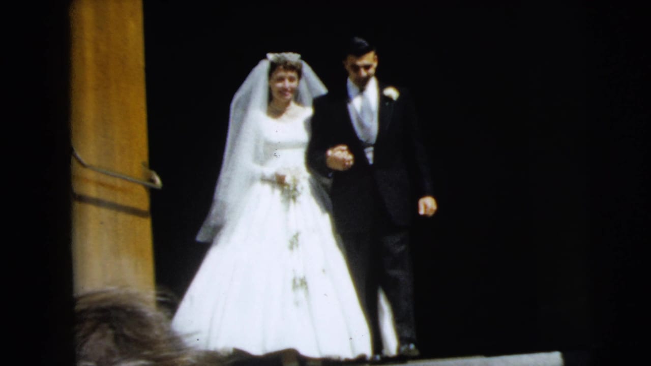 Bride and groom descend steps together against a dark background.