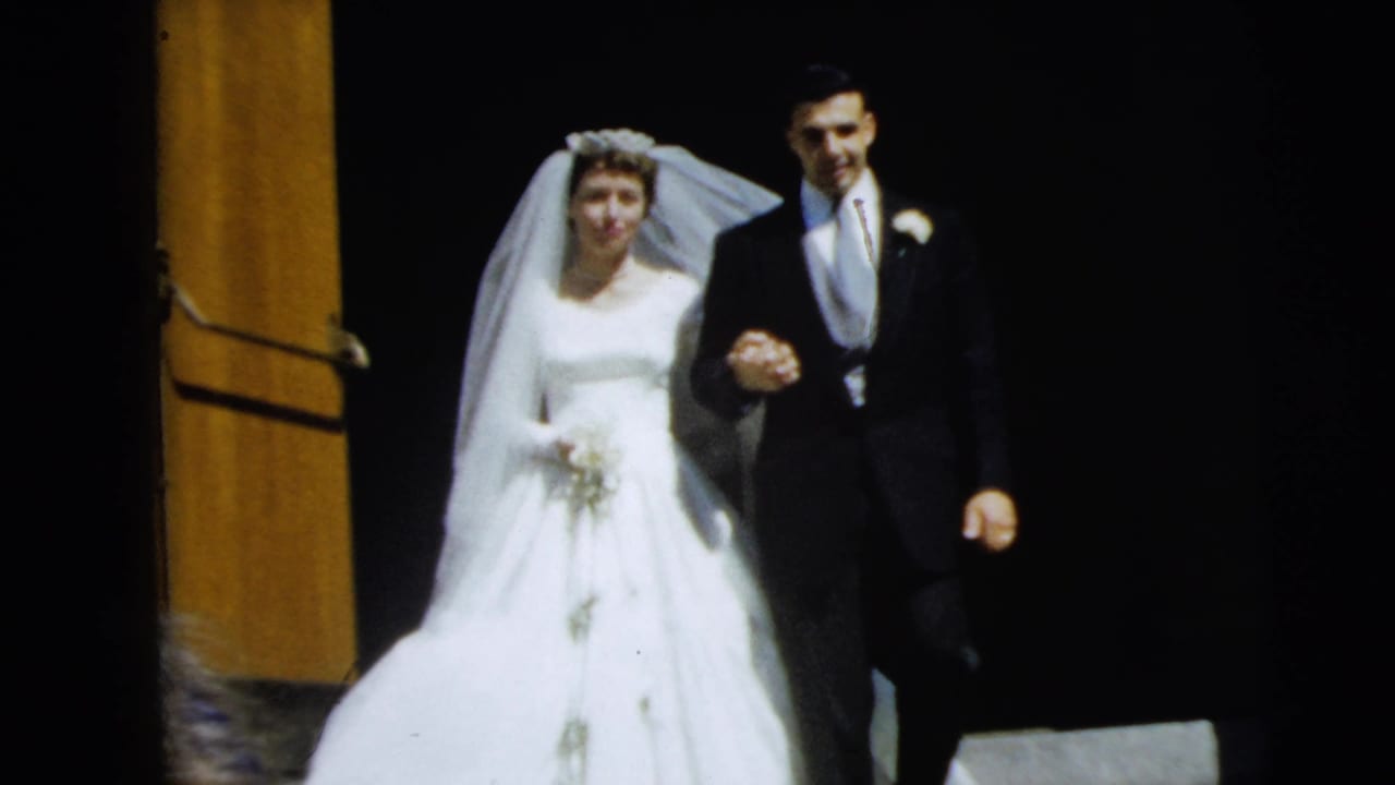 Bride and groom walk arm in arm down steps beside a wood door frame.