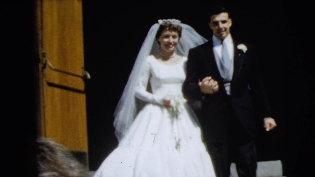 The bride and groom move closer to the camera in this 1962 Camden wedding footage, holding hands as they descend the steps.